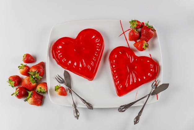 Sweet gelatin hearts dessert in the white dish with fresh strawberries