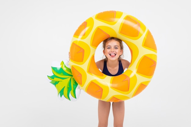 Sweet girl about to swim in the sea with a rubber ring and a mattress on an isolated white