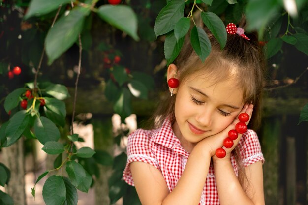 Sweet girl folded hands as if in prayer holding a bunch of cherries in palms