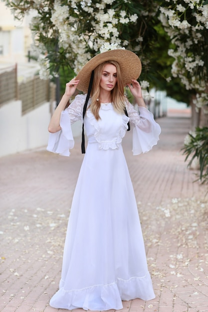 Sweet girl in a hat and white dress with white flowers