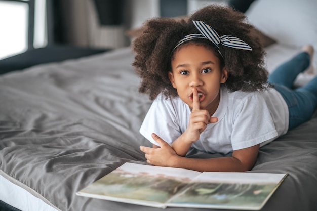 A sweet girl showing silence sign and looking excited