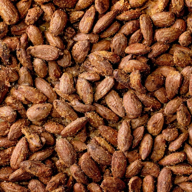 Sweet glazed honey and cane sugar roasted almond nuts on backing paper Sweet snack Close up food background Top view Square image