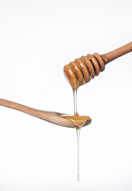 Photo sweet golden honey flowing on a wooden spoon