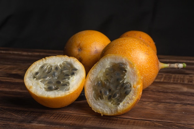 Sweet granadilla or grenadia passion fruit. Whole and cut in half exotic fruits on wooden board