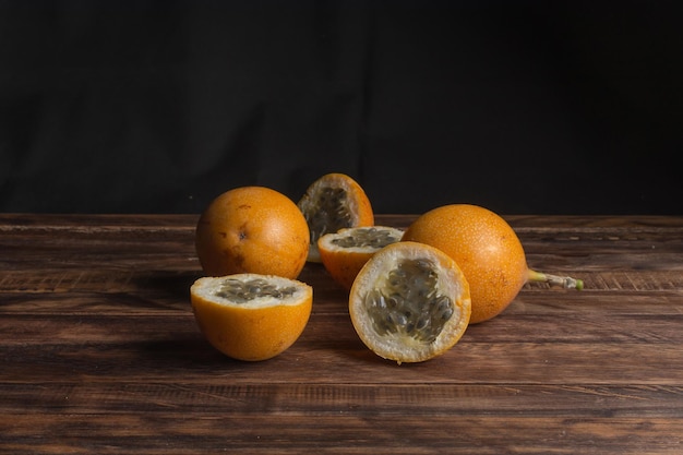 Sweet granadilla or grenadia passion fruit. Whole and cut in half exotic fruits on wooden board