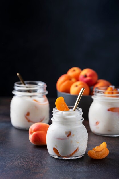 Sweet healthy yogurt with apricots on the dark table, 