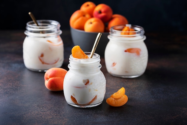 Sweet healthy yogurt with apricots on the dark table