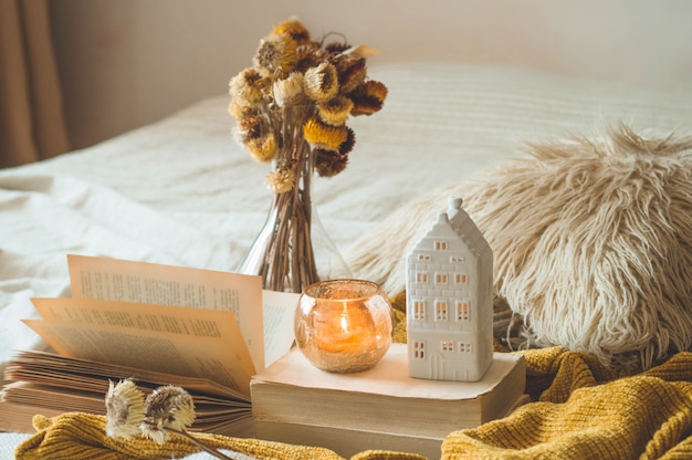 Sweet Home. Stillevendetails in huisbinnenland van woonkamer. Gedroogde bloemenvaas en kaars, herfst decor op de boeken. Lezen, rusten. Gezellig herfst- of winterconcept.