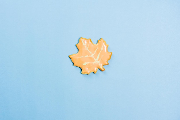 Sweet homemade leaf cookie with icing isolated on blue background minimal flat lay composition