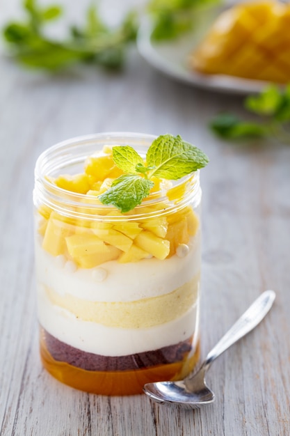 Sweet homemade Mango dessert, cheesecake, trifle, mouse in a glass jar on a light wood