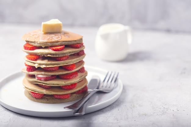 Foto pancakes dolci fatti in casa con fragole e burro. pronto per la colazione