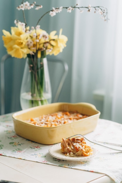 Sweet homemade pastries in a yellow baking dish against the background of yellow spring flowers bri