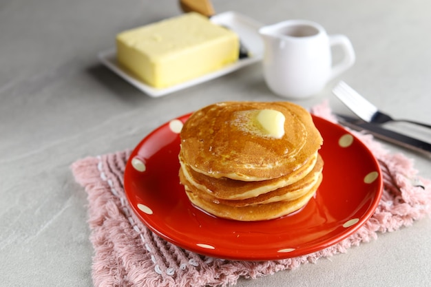 Pila di frittelle dolci fatte in casa con burro e sciroppo di miele per colazione