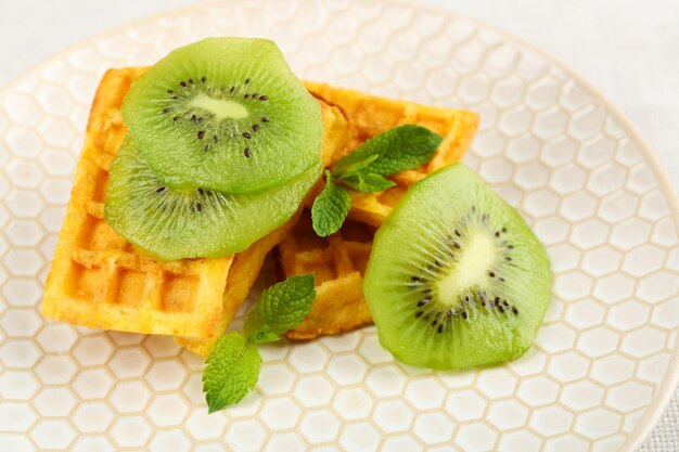 Sweet homemade waffles and fresh kiwi fruit on plate closeup