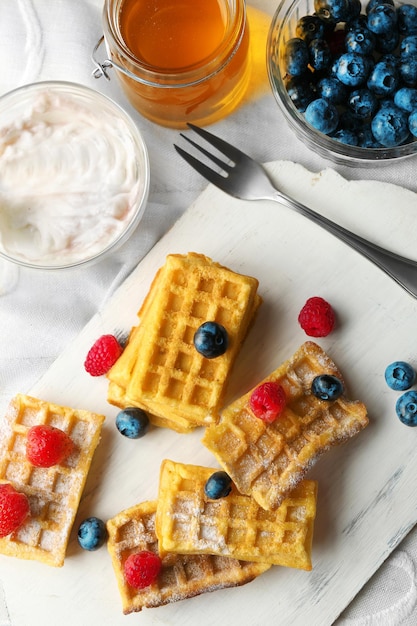 Sweet homemade waffles on tray on light background