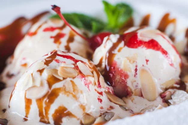 레스토랑에서 제공되는 캐러멜과 과일 시럽을 곁들인 달콤한 아이스크림 볼 맛있는 차가운 디저트로 장식된 신선한 민트 잎이 클로즈업 사진