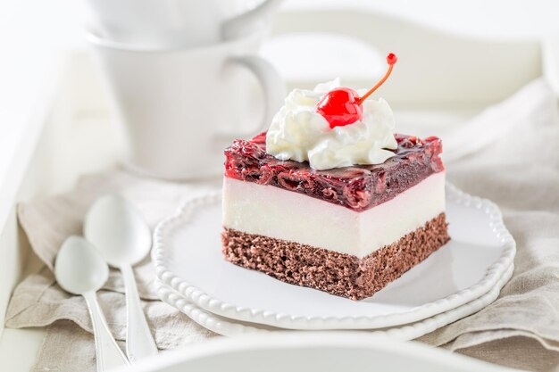 Sweet jelly cherry cake with cream on white plate