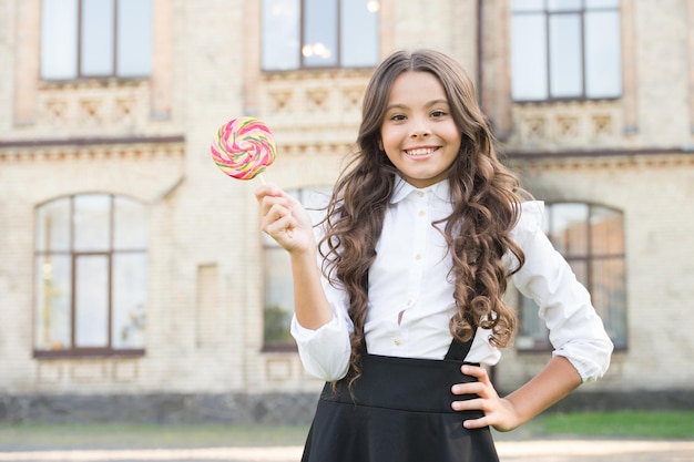 Sweet joy Happy kid with sweet candy Happy childhood Kid child holding lollipop candy Sweets concept Happy kid with candy outdoors having fun Schoolgirl relaxing School nutrition Sugar diet