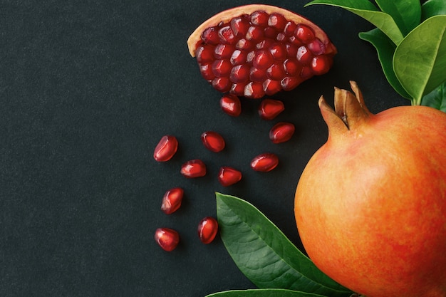 Sweet and juicy Indian pomegranate on black granite table in top view with copy space.