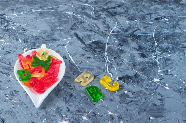 Sweet letters shaped marmalades on a marble background . 