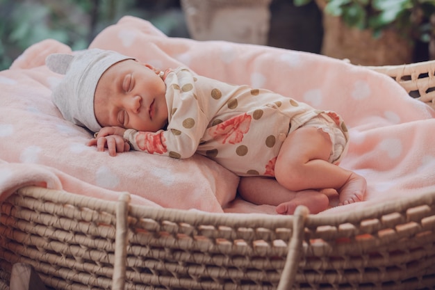 Sweet little baby sleeping in a basket on pink blanket