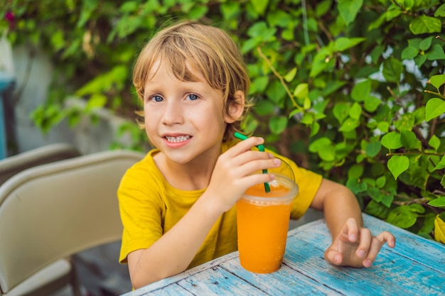 Sweet little caucasian boy eating pancakes and drinking orange juice