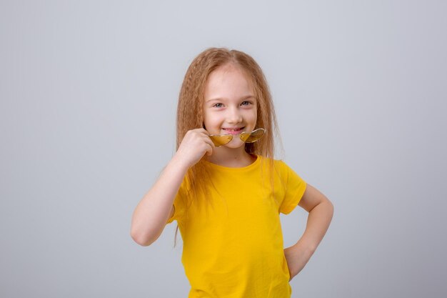 写真 サングラスをかけた甘い陽気な幸せな女の子は白い背景に横たわって幸せです