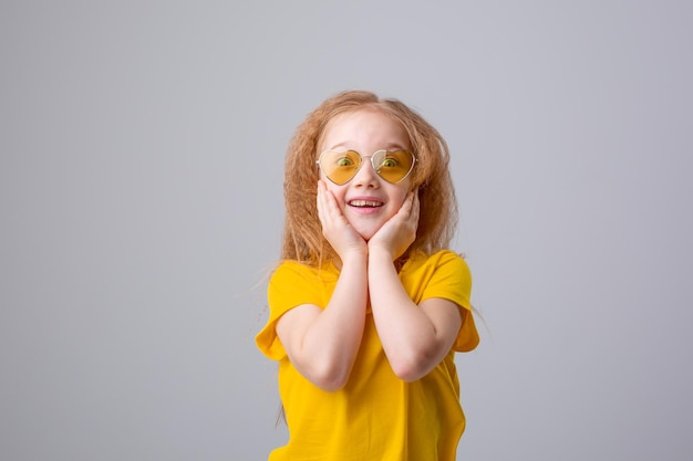 sweet little cheerful happy girl in sunglasses is happy lying on a white background