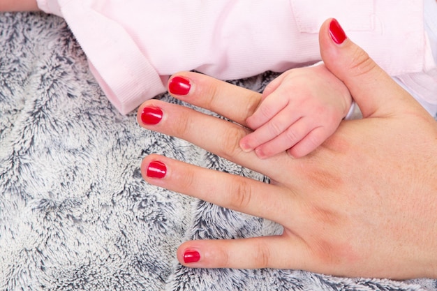 Sweet little family fingers of newborn baby hold adult hand mother