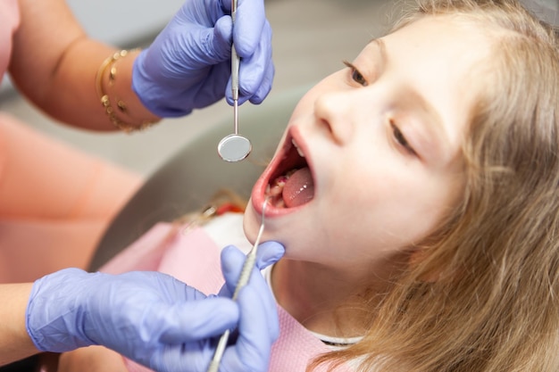 치과 의자 에 있는 달 한 어린 소녀 치과 의사는 어린이 의 환자 의 치아 를 검사 한다