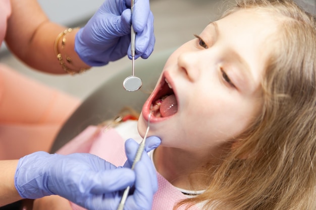 Sweet little girl in the dental chair The dentist examines the teeth of the child's patient Pediatric dentistry