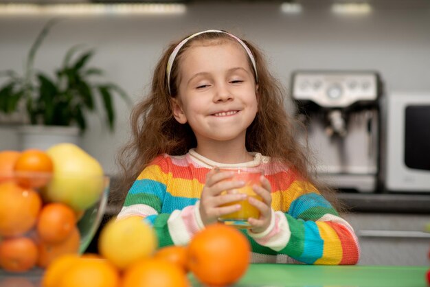 甘い女の子はオレンジの新鮮な健康的な食事家族の新鮮な果物を飲みます