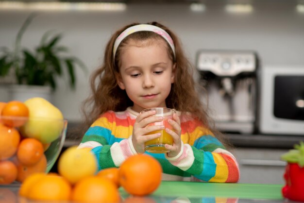 甘い女の子はオレンジの新鮮な健康的な食事家族の新鮮な果物を飲みます