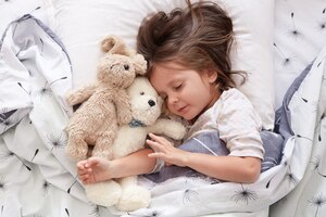 Sweet little girl sleeping with toys in crib. close up portrait of infant sleeping in cot. beautiful toddler sleeping with toy bear and dog