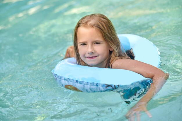 Sweet little girl swimming on a tube and smiling