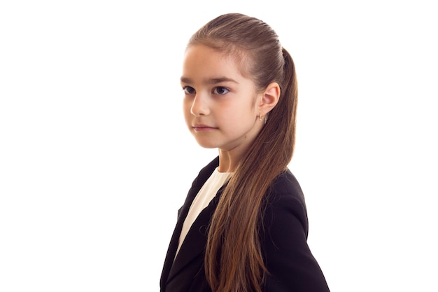 Sweet little girl with long brown ponytail in white Tshirt and black jacket on white background