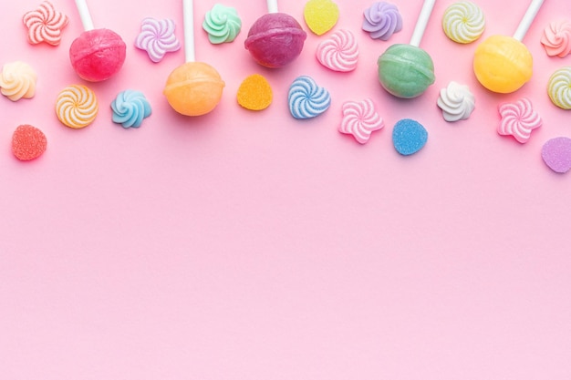 Sweet lollipops and candies on pink background