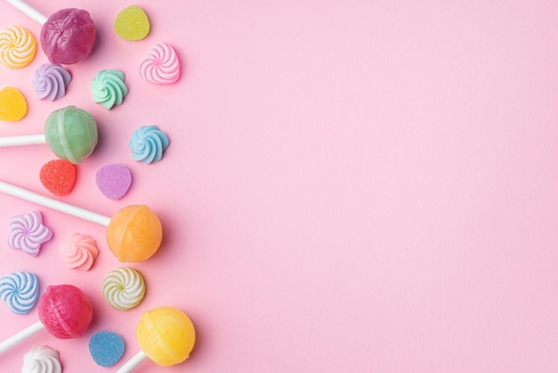 Sweet lollipops and candies on pink background