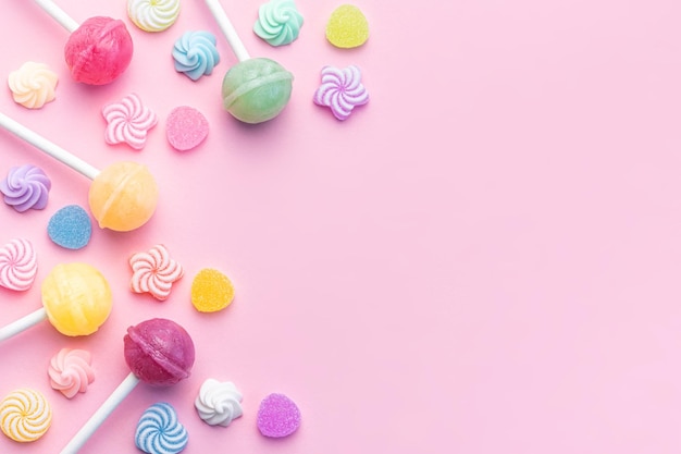 Sweet lollipops and candies on pink background