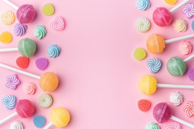 Sweet lollipops and candies on pink background