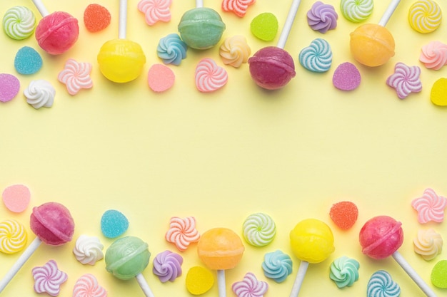 Sweet lollipops and candies on yellow background