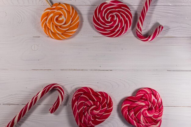 Sweet lollipops on white wooden background. Top view