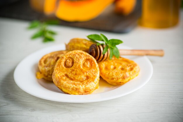 sweet lush pumpkin pancakes with honey in a plate on a wooden table