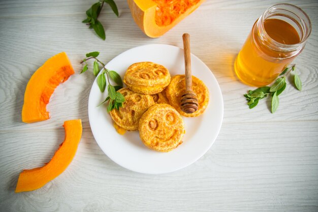 Sweet lush pumpkin pancakes with honey in a plate