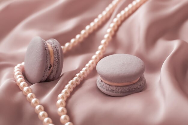 Sweet macaroons and pearls jewellery on silk background\
parisian chic jewelry french dessert food and cake macaron for\
luxury confectionery brand holiday gift