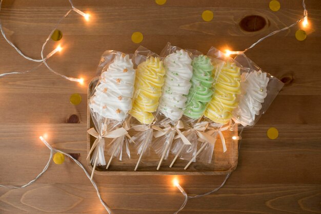 Sweet meringue in hand, on a stick in the form of a Christmas tree