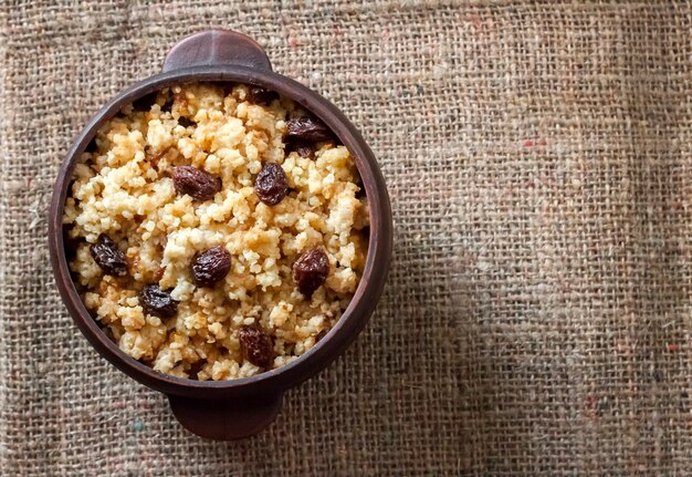 Porridge di miglio dolce con uvetta scura in ciotola rustica in ceramica