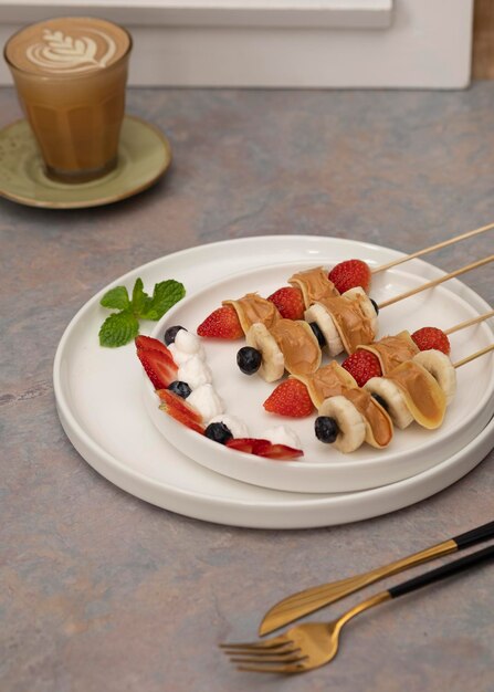 Photo sweet mini pancakes, served with peanut butter spread, strawberry and blue berry in a skewer.closeup