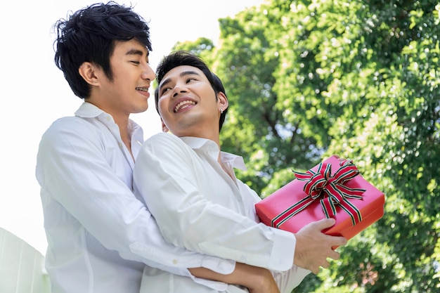 愛の甘い瞬間。アジアの同性愛者のカップルの抱擁と彼氏へのサプライズボックスギフト。コンセプトLGBTゲイ。
