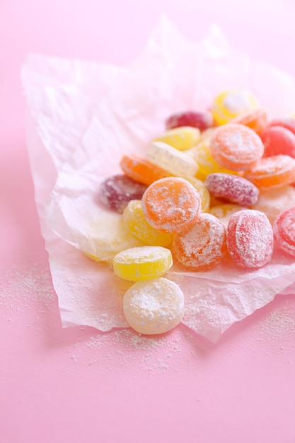 Sweet multicolor candies on paper on color background